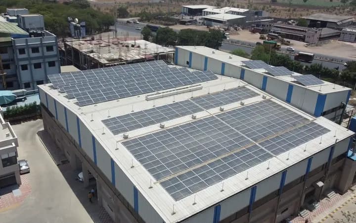 Wide aerial orbit of a completed factory rooftop solar installation