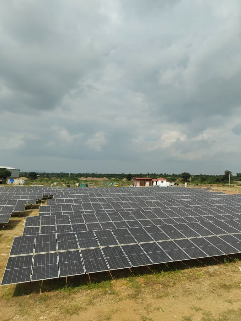 Rows of ground-mounted solar panels stretching toward a rural horizon